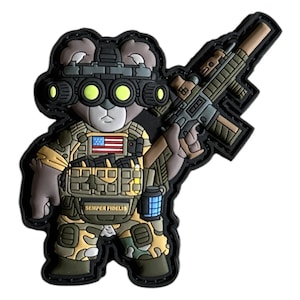 May include: A patch featuring a teddy bear in military gear, including night vision goggles and a tactical vest. The bear is holding a rifle and has an American flag patch. The text "SEMPER FIDELIS" is visible.