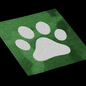 May include: A green square mat with a white paw print design. The paw print is composed of five white ovals and a larger white pad. The mat has a textured appearance and is set against a black background.