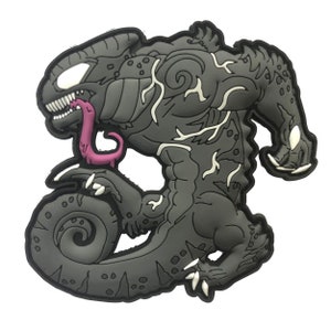 May include: A gray and black monster-like figure with a long, pink tongue and white accents. The figure has sharp teeth and claws, with a muscular build. The design is a cartoonish representation of a creature.