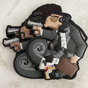 May include: A collection of cartoon patches featuring characters in suits holding guns. One character has long black hair and a briefcase. Another patch shows a character with a Pop-Tart and a notepad. The patches are in shades of gray, black, brown, and tan.