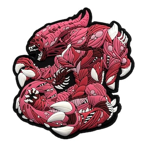 Op de afbeelding: Een gedetailleerde patch met een monsterlijk wezen in roze en rode tinten, met scherpe witte klauwen en tanden. Het ontwerp heeft een gelaagde, getextureerde uitstraling, omlijnd in zwart.