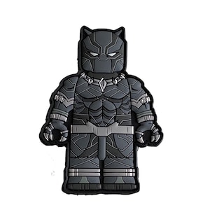 May include: Black Panther Lego minifigure patch. The patch is black and gray with a detailed design of the character's costume.