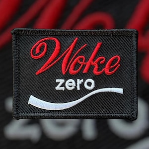 May include: Black embroidered patch with white stitching. The patch features the text "Woke Zero" in red and white.