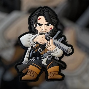 May include: A cartoon patch depicting a character with long black hair, a white shirt, and brown boots, holding a gun. The character has a stern expression and is dressed in a historical outfit. The patch has a black border.