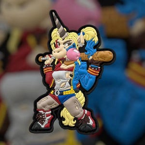 Pode incluir: Um remendo colorido com um unicórnio vestindo uma camisa listrada rosa e branca, uma jaqueta azul e shorts vermelhos e azuis. O unicórnio está segurando um taco de beisebol e soprando uma bolha.