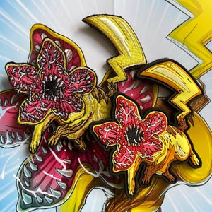 May include: Embroidered patches featuring Demogorgon flower creatures with red, pink, and black details. Also, a yellow lightning bolt patch. The patches are on a background with a cartoon-style design.
