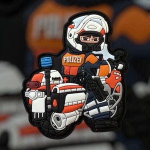 Puede incluir: Un parche colorido con un policía de dibujos animados en una motocicleta. El oficial lleva un casco blanco y un chaleco naranja. La palabra "POLIZEI" es visible. La motocicleta es blanca, naranja y negra.