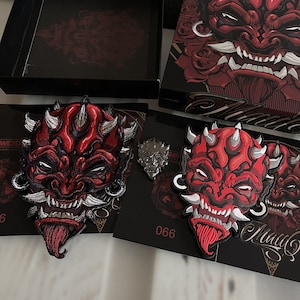 May include: Two red and black embroidered patches featuring a demon face with horns and fangs. The patches are on a black background with the text "Maui" and "066".
