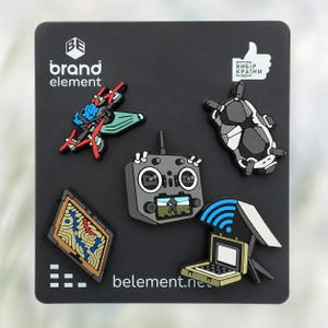 May include: A set of five rubber pins on a black display card featuring a drone, a remote control with a screen, a grey and black drone body, a topographic map, and a laptop with a blue Wi-Fi symbol. The card includes the text brand element and belement.net.