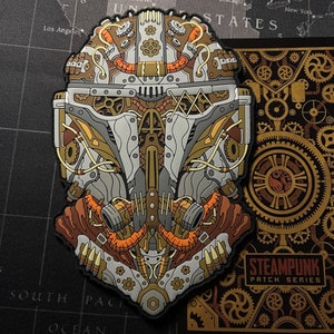 May include: A detailed steampunk patch in brown, grey, and gold, featuring mechanical elements like gears and tubes. The design is intricate and industrial. A matching card with the text "STEAMPUNK PATCH SERIES" is also visible.