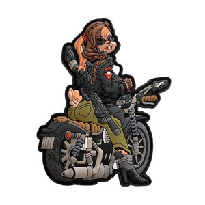 May include: A patch depicting a cartoon rabbit with brown hair and sunglasses, riding a motorcycle. The rabbit is dressed in a black jacket and olive green trousers, holding a rifle. The motorcycle is black and grey.
