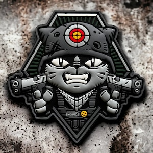 Könnte beinhalten: Ein schwarzer und grüner taktischer Patch mit einer Comic-Katze, die einen Helm mit Zielscheibe trägt und zwei Pistolen hält. Die Katze trägt eine taktische Weste mit dem Aufdruck "HOORAY".