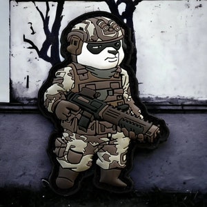 May include: A black and white panda wearing a camouflage military uniform and helmet, holding a black rifle. The panda is standing on a gray surface.