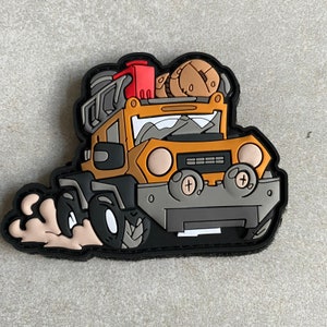 May include: A yellow cartoon off-road vehicle with a black bumper and black tyres. The vehicle is carrying a red petrol can, a brown tyre, and a brown object on top. The vehicle is driving through a patch of dirt.