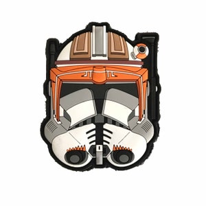 Peut inclure: Image détaillée et colorée d'un casque de Clone Trooper de Star Wars. Le casque présente une base blanche avec des accents orange, gris et marron, et un contour noir. Le design rappelle le personnage Captain Rex.