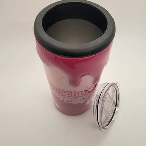 May include: A pink stainless steel tumbler with a black lid and a white design that says "Rosebud". The tumbler has a clear plastic lid with a black ring around the edge.