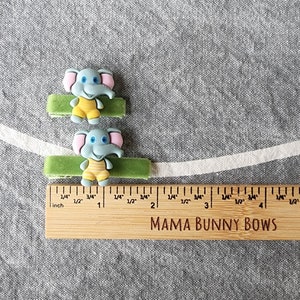 May include: Two green fabric hair ties with blue and yellow elephant charms. The hair ties are 5 cm long. The ruler reads "MAMA BUNNY BOWS".