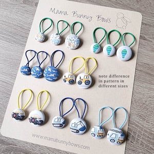 May include: A set of 10 colorful hair scrunchies with different patterns. The scrunchies are made of fabric and have a button-like design. The patterns include animals, vehicles, and geometric shapes. The scrunchies are arranged in rows on a brown surface. The text "Mama Bunny Bows" is written at the top of the surface. The text "note difference in pattern in different sizes" is written in the middle of the surface. The text "www.mamabunnybows.com" is written at the bottom of the surface.