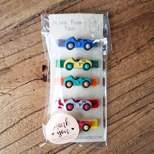 May include: Set of five colorful hair clips with a vintage car design. Each clip features a different color car with a black stripe and white wheels. The clips are packaged in a clear plastic bag with a thank you tag that reads "Thank you for supporting my small business".