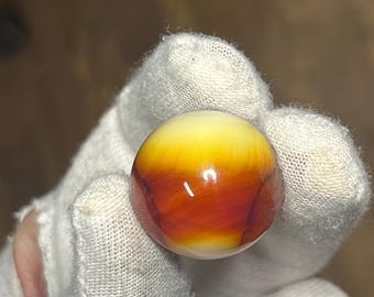 May include: A round, yellow, orange, and red marble with a white center.