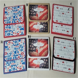 May include: A collection of six small, handmade card holders. Designs include medical symbols, American flags, and heart rate patterns. The holders have red, blue, and black borders, with a flap closure. The overall theme is medical and patriotic.