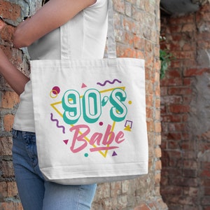 May include: White tote bag with a 90's Babe design in colorful, retro-style lettering and geometric shapes.