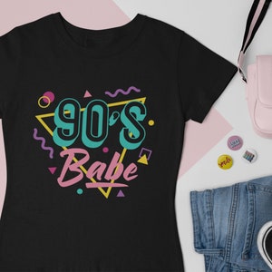 May include: Black t-shirt with a graphic design of a triangle with the text "90's Babe" in colorful letters and geometric shapes.
