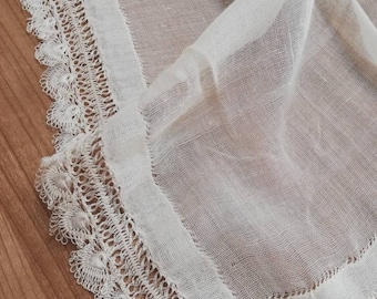 May include: White sheer fabric with a delicate lace trim. The lace is intricate and has a scalloped edge.