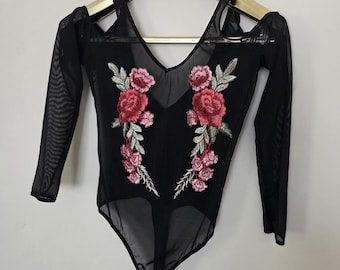 May include: Black bodysuit with long sleeves and a V-neck. The sheer mesh fabric features embroidered red and pink floral designs on the front. The shoulders have a cut-out design.