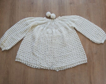 May include: A white crocheted sweater with a textured design and a scalloped hem.