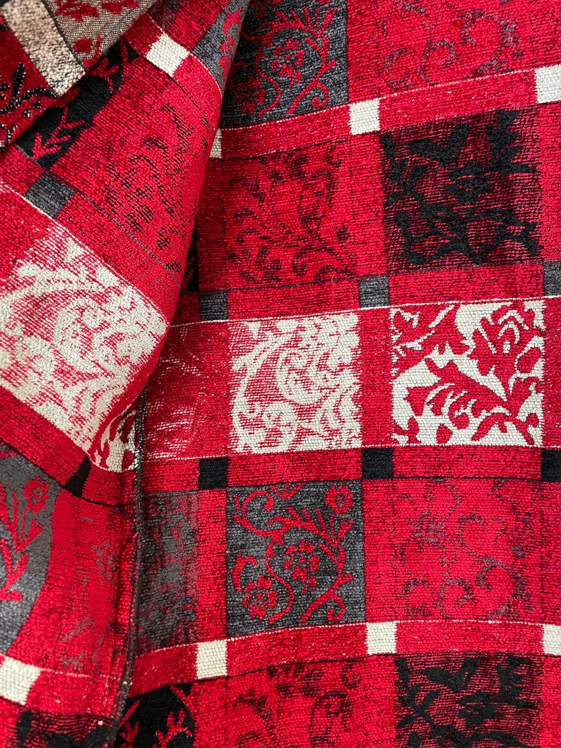 May include: Red, black, and white checkered fabric with a floral pattern. The fabric has a textured surface.