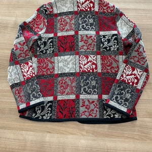 May include: A red, black, and white patterned jacket with a black collar and long sleeves.