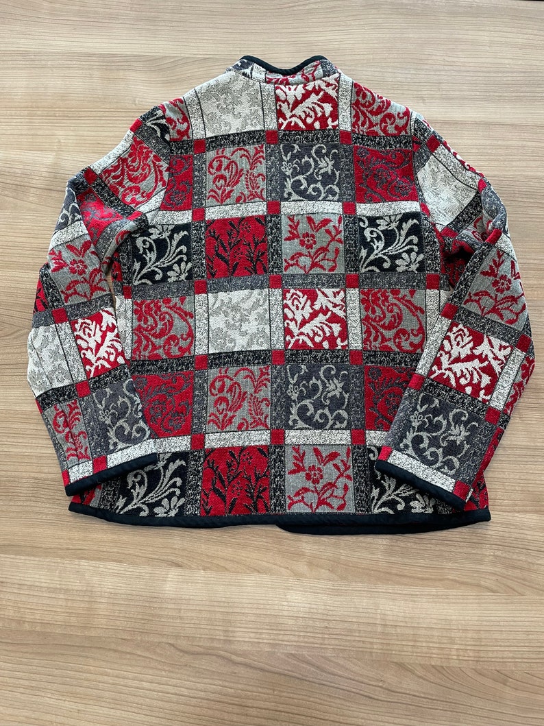 May include: A red, black, and white patterned jacket with a black collar and long sleeves.