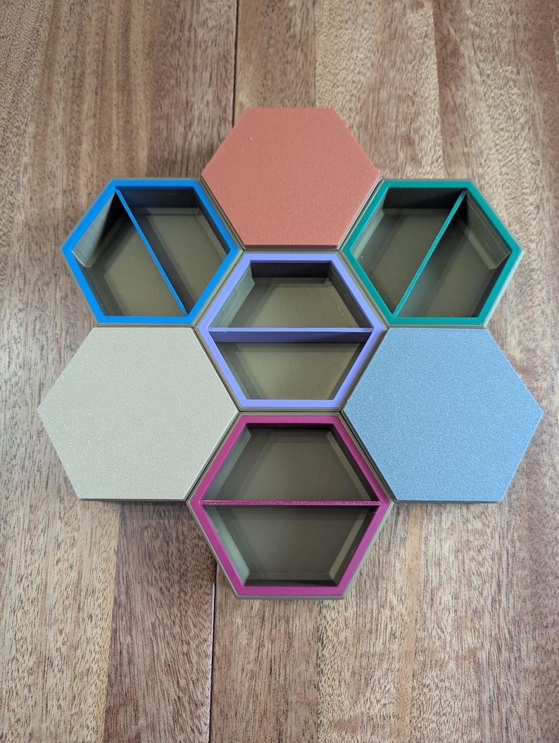 May include: A set of seven hexagonal shelves in various colors, including blue, coral, green, lavender, beige, and light blue. Each shelf has a dark interior and a colored border, arranged in a honeycomb pattern on a wooden surface.