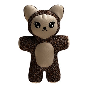 May include: A brown and beige plush teddy bear with a floral pattern. The bear has large black eyes and a black nose.