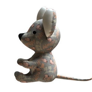 May include: A gray plush mouse toy with a pink and white pattern. The pattern features pigs and the text "Zzz..." and "Woop!"