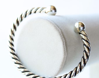 Op de afbeelding: Een zilveren gedraaide armband met afgeronde uiteinden.