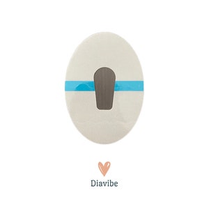 Peut inclure: Un patch ovale blanc avec une bande bleue et une découpe grise au centre. Le patch porte le mot "Diavibe" imprimé en dessous.