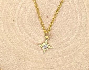 May include: A gold chain necklace with a small, sparkling star pendant.