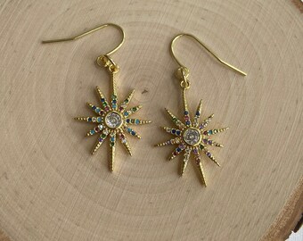 May include: Gold starburst earrings with a clear crystal center and colorful rhinestones around the edges.