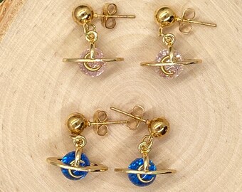 May include: A pair of gold earrings with a dangling orb design. The orbs are adorned with sparkling crystals, one pair is pink and the other is blue.