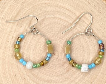 May include: A pair of silver hoop earrings with a beaded design. The beads are in shades of blue, green, gold, and white.