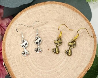 May include: Two pairs of cat-shaped earrings. One pair is silver and the other is gold.