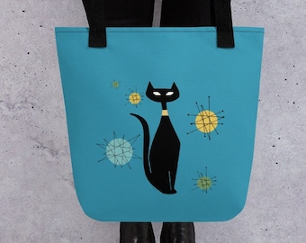 May include: A blue tote bag with a black cat and yellow and green starburst designs. The cat has a black collar.