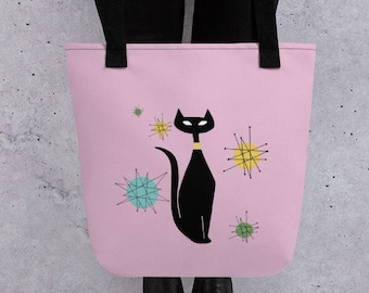 May include: A pink tote bag featuring a black cat illustration with a gold collar and mid-century modern starburst designs in yellow, teal, and green. The bag has black handles.