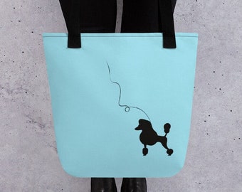 May include: A light blue tote bag with a black silhouette of a poodle on a leash. The bag has black handles.