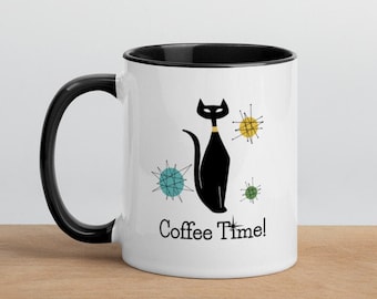 May include: White ceramic coffee mug with a black rim and handle. The mug features a black cat with a yellow collar sitting in front of a blue, green, and yellow abstract design. The text "Coffee Time!" is printed below the cat.