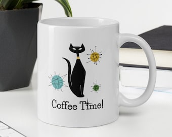 May include: White ceramic coffee mug with a black cat illustration and colorful mid-century modern style stars. The mug has the text "Coffee Time!" printed on the front.