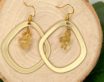 May include: Gold hoop earrings with a dangling cluster of light brown gemstone beads.