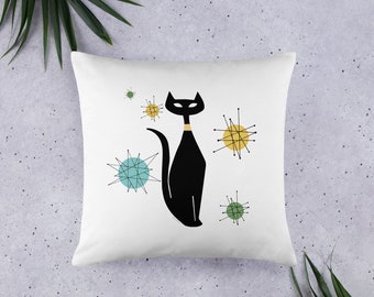 May include: White pillow with a black cat silhouette and colorful mid-century modern starburst designs. The cat has a yellow collar.